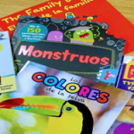 A pile of children's books on a desk. The pile includes "Los colores de la selva" and "Monstruos".